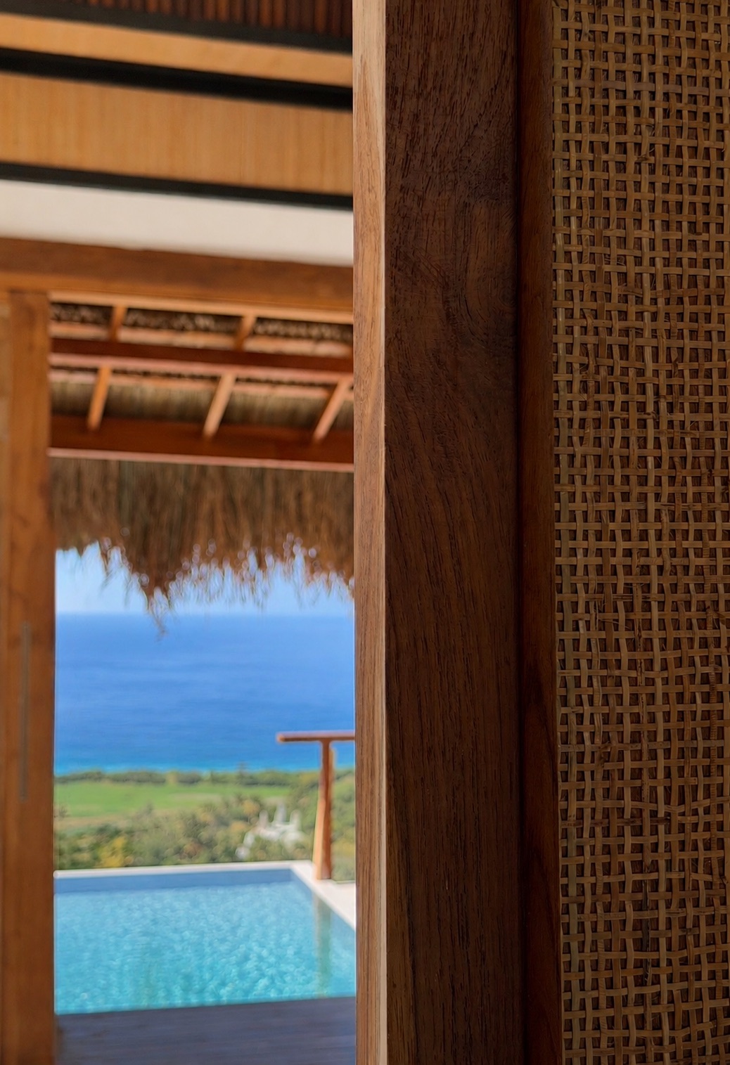 View through an open teak door to the infinity pool and the sea