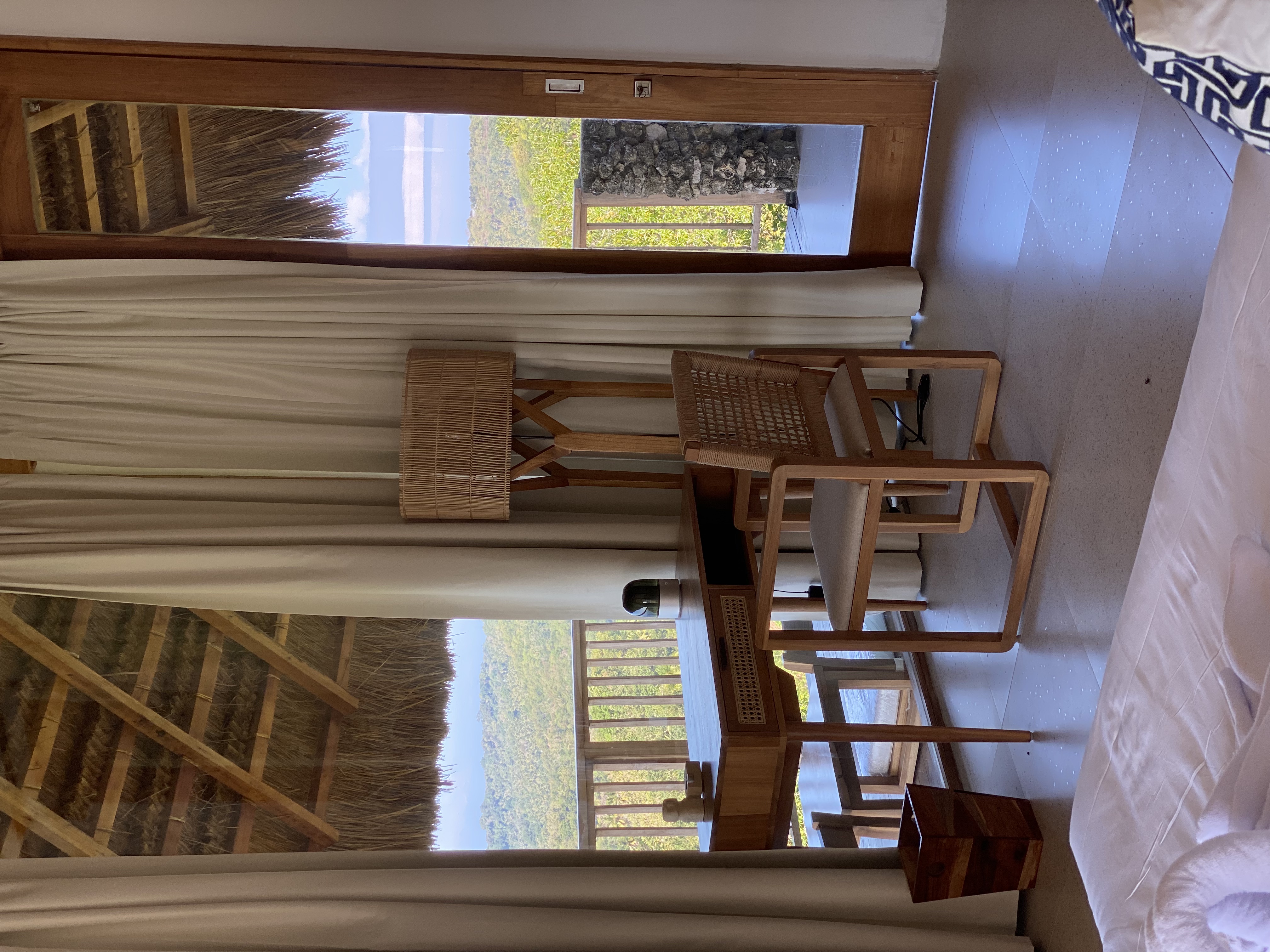 Bedroom desk with rattan chair and lamp, sea view beyond