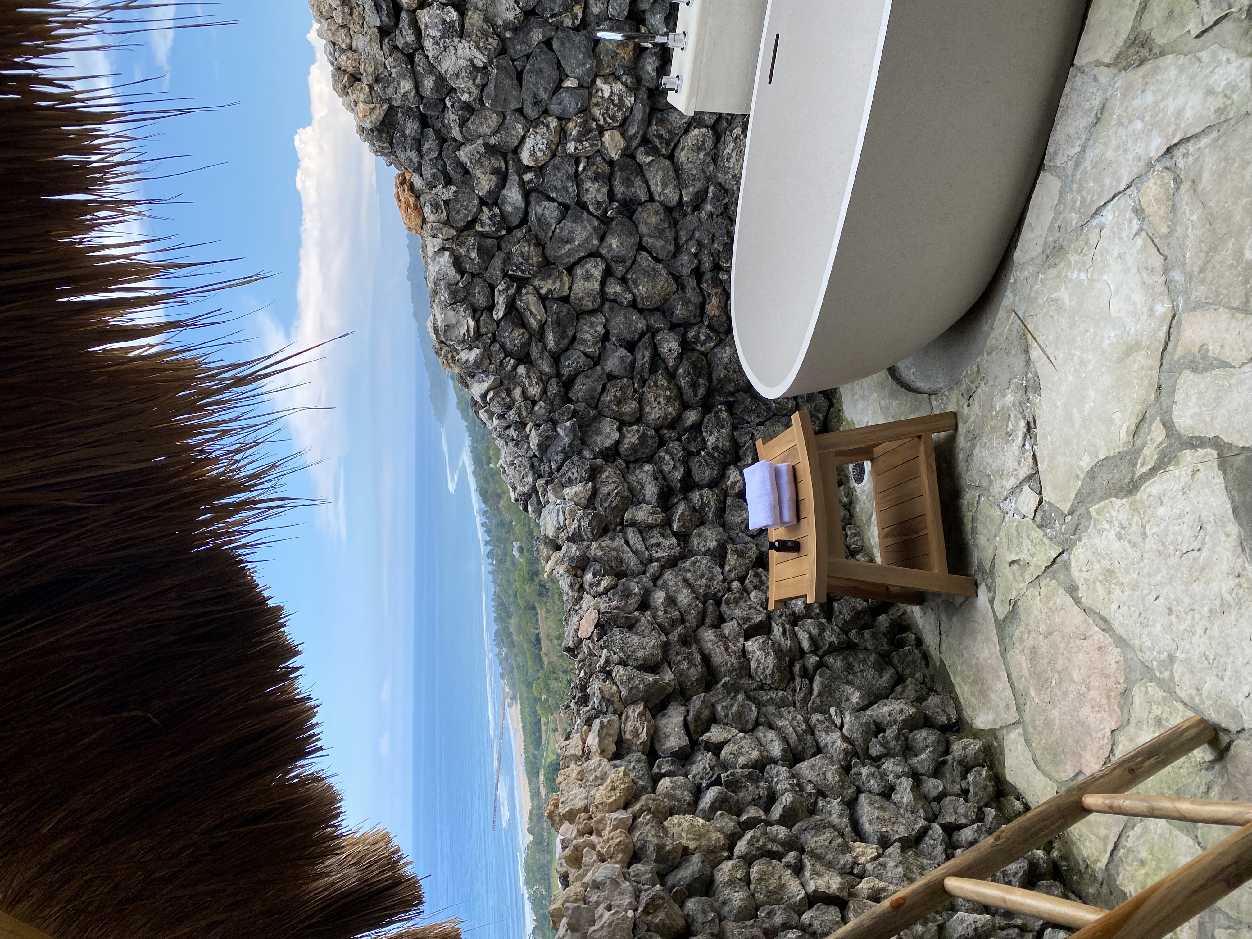 Outdoor bathtub under a thatch roof with sea view