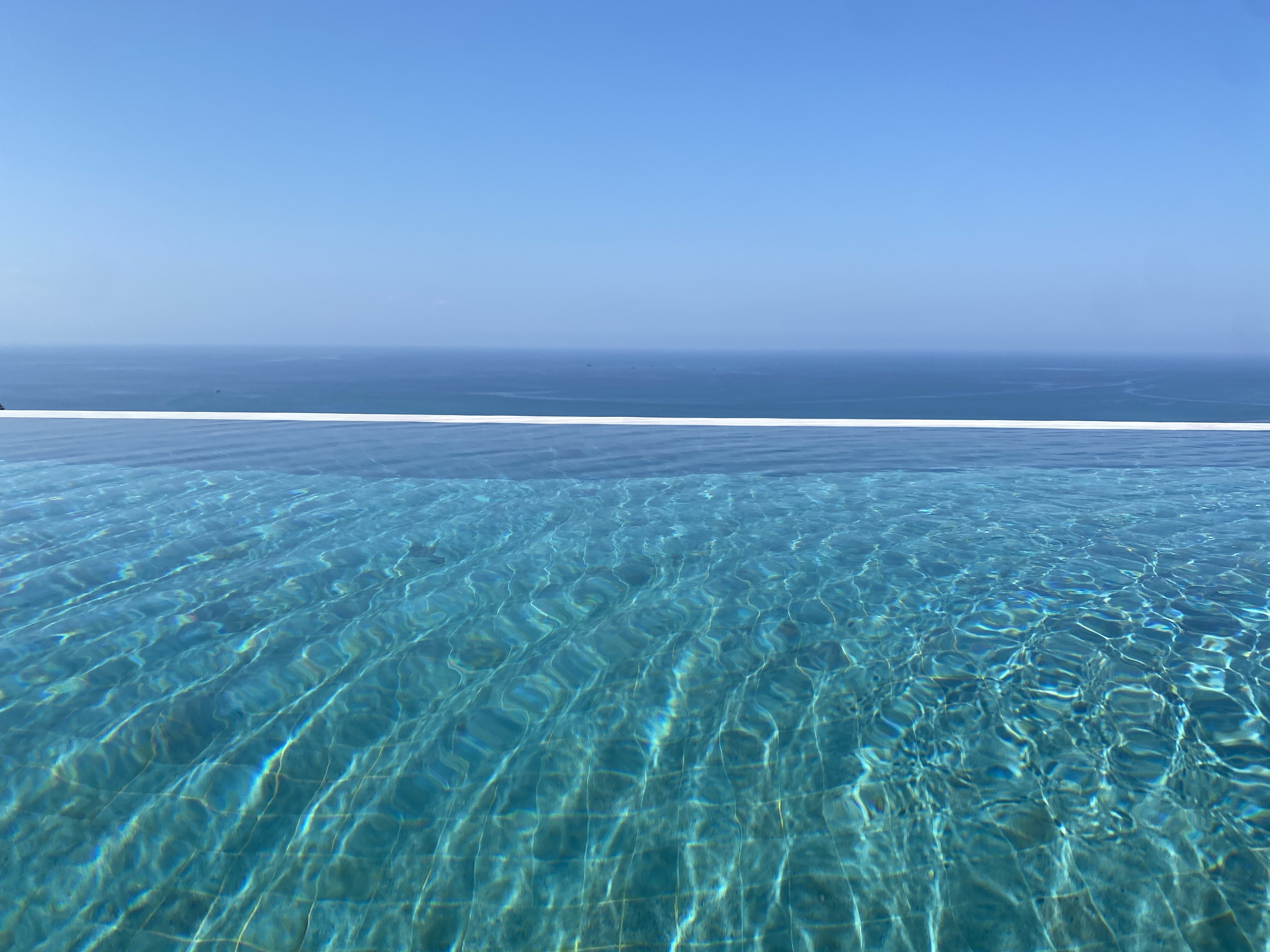 Infinity pool edge meeting the sea horizon at Umarato