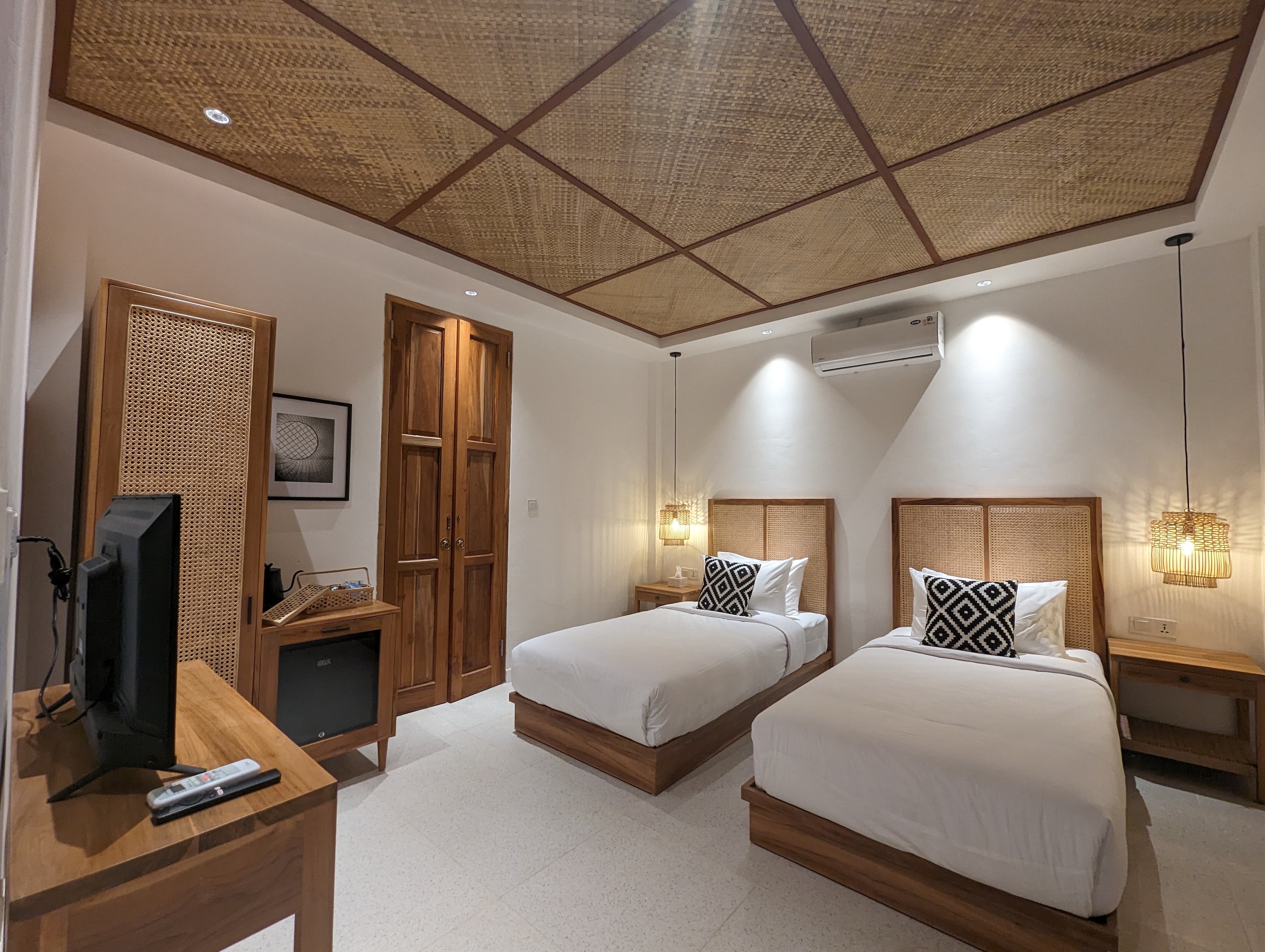 Twin beds with cane headboards under a rattan panel ceiling
