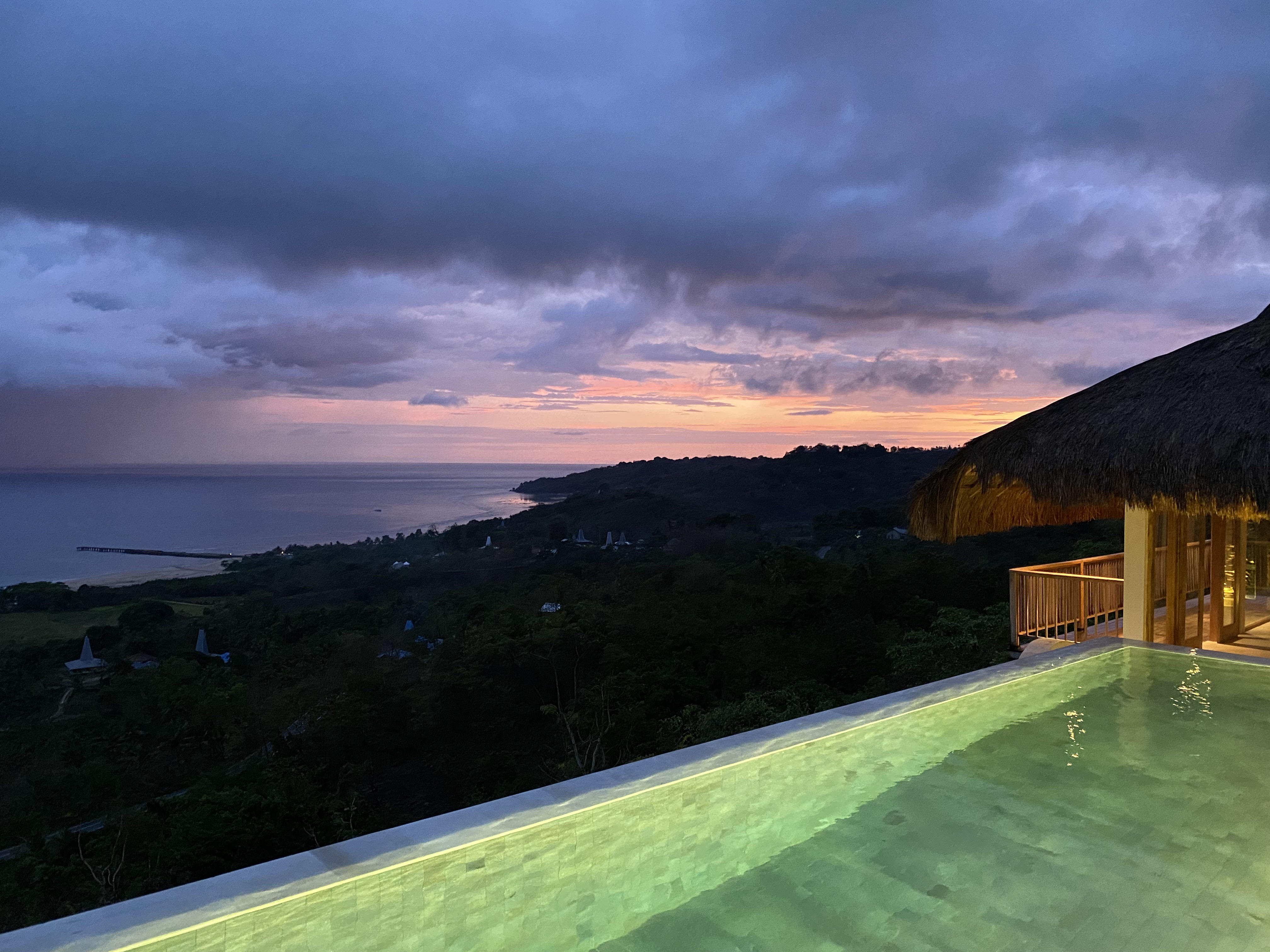Infinity pool at dusk with the thatched pavilion