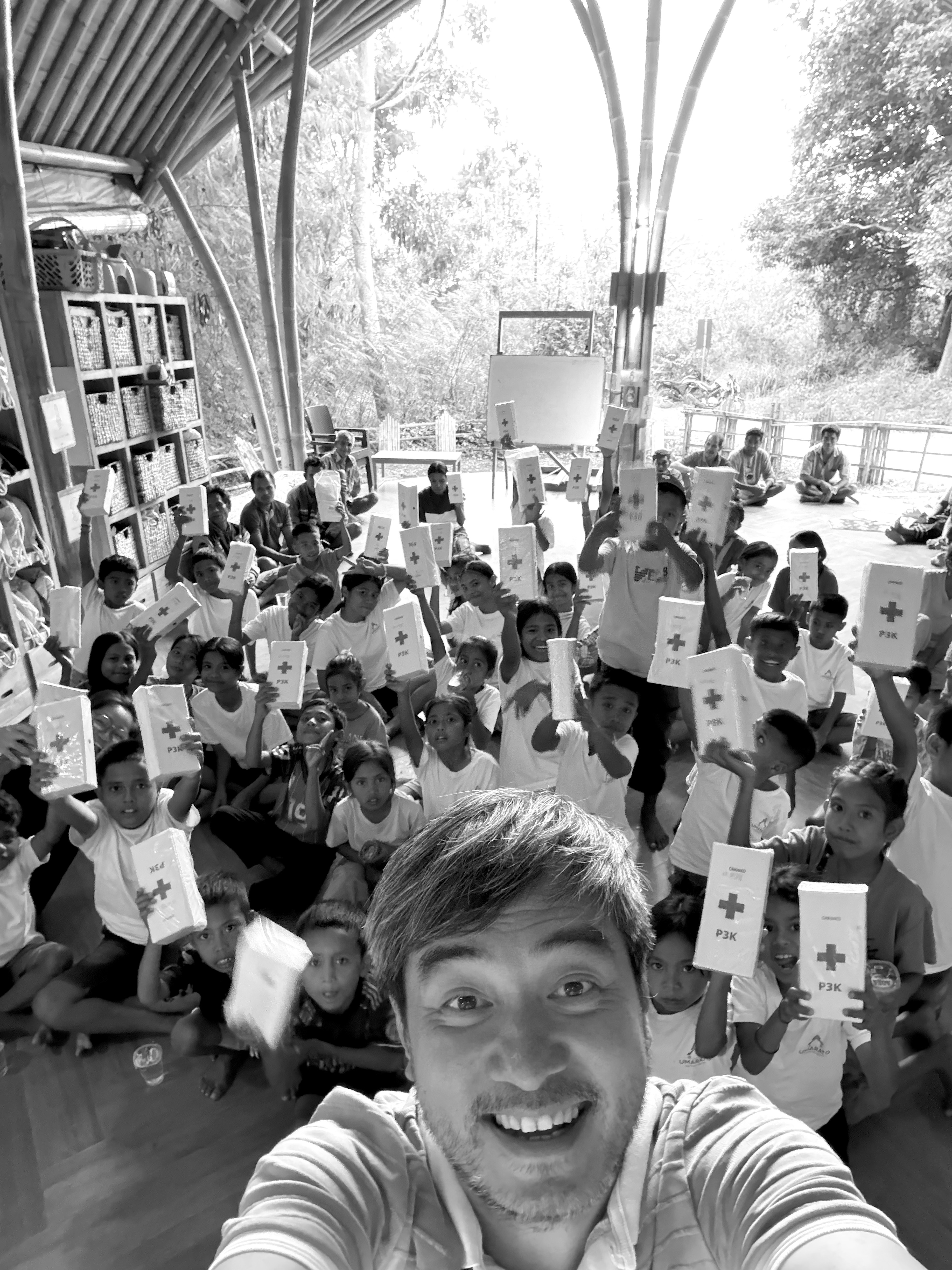 Selfie with the learning center children proudly holding up first-aid kits marked P3K