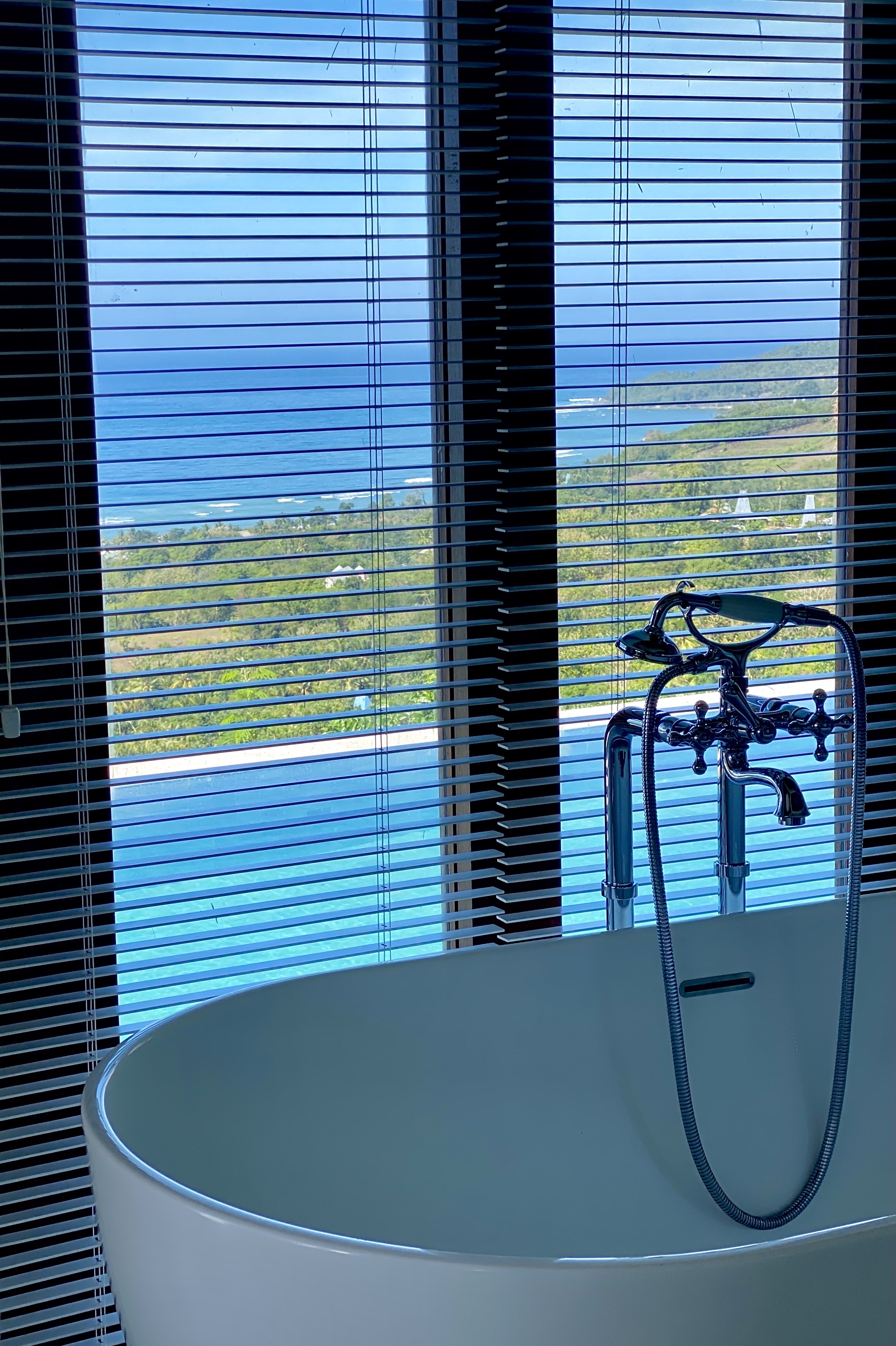 Bathtub with vintage chrome tap behind venetian blinds